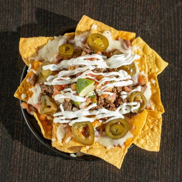 Señor Pollo's nachos with ground beef, melted cheese, jalapeños, pico de gallo, sour cream, and lime.