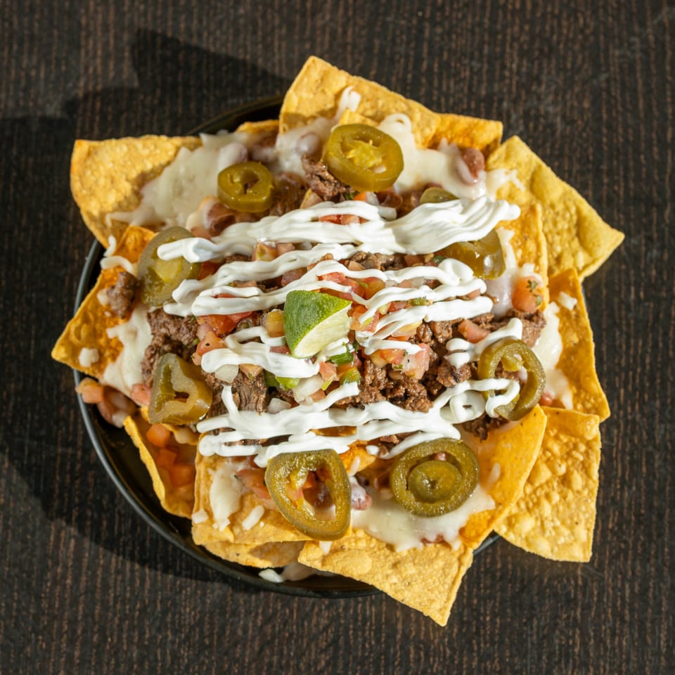Señor Pollo's nachos with ground beef, melted cheese, jalapeños, pico de gallo, sour cream, and lime.